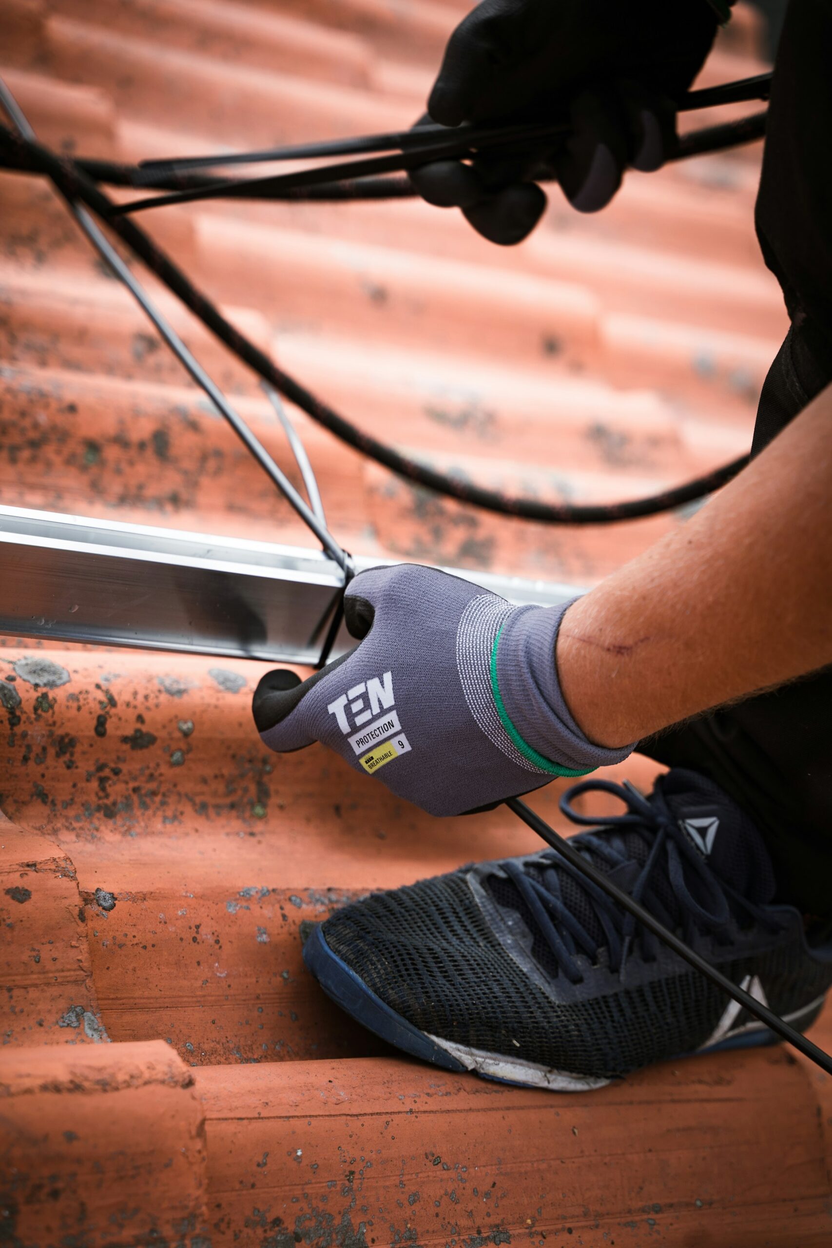 Optimierer für PV - Präzision schon bei der Installation Installateur montiert Kabel und Komponenten auf Ziegeldach – Vorbereitung für Leistungsoptimierer in Photovoltaikanlage