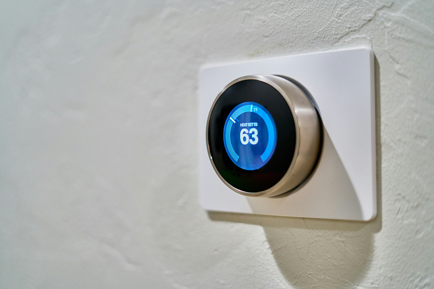 Smartes Thermostat an weißer Wand mit Anzeige auf 63 Grad – moderne Heizungssteuerung