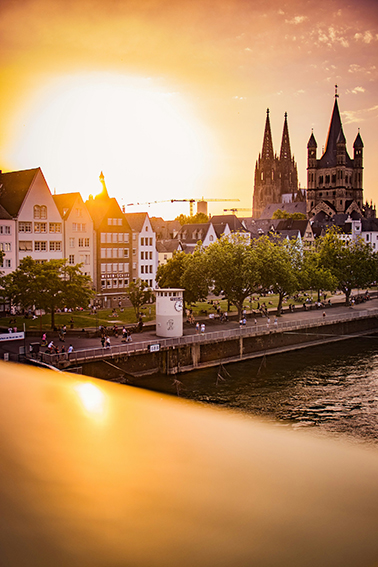 Skyline Köln bei Sonnenuntergang (oder Sonnenaufgang) mit Groß St. Martin und Rhein. Der Blick symbolisiert die Energiewende und Solarenergie in Köln.
